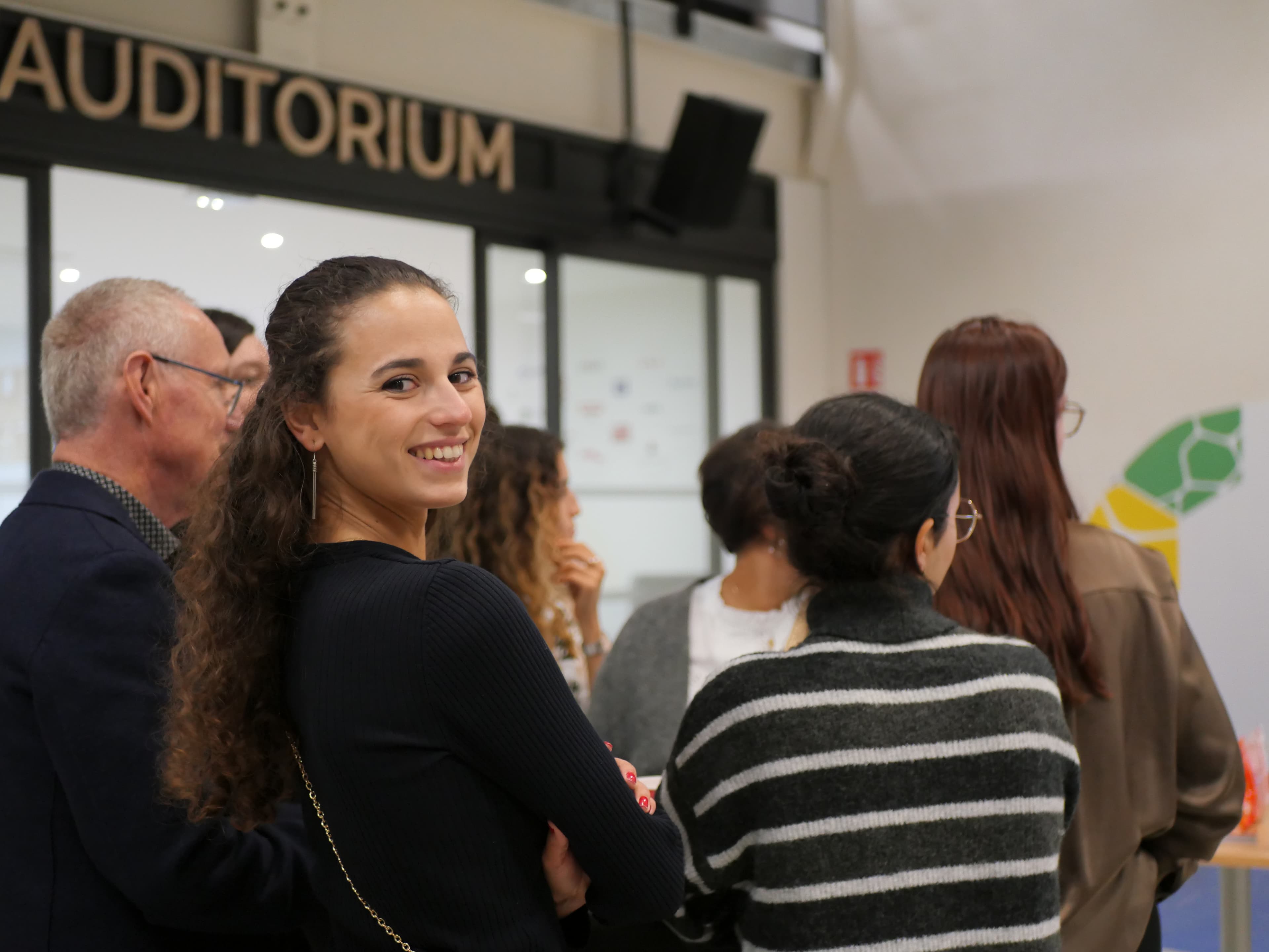 Étudiante Propulseo souriante lors d’un événement en auditorium, entourée de la communauté.